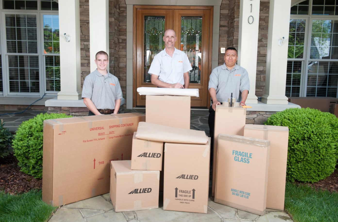 Three Allied Movers Behind Boxes in Front of a Home Porch