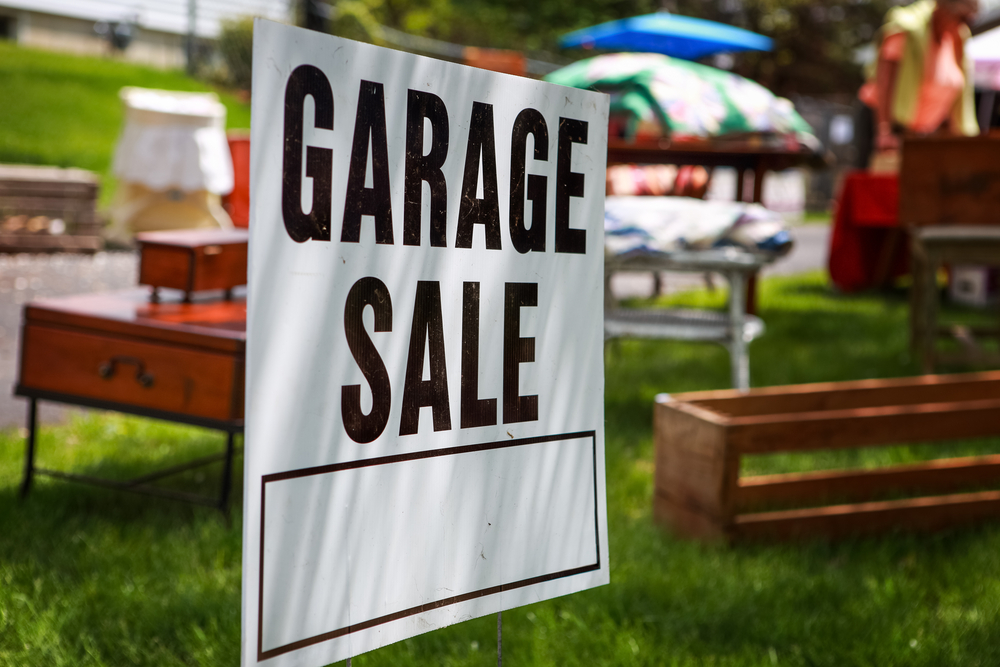 Garage Sale Sign in Yard with Items for Sale