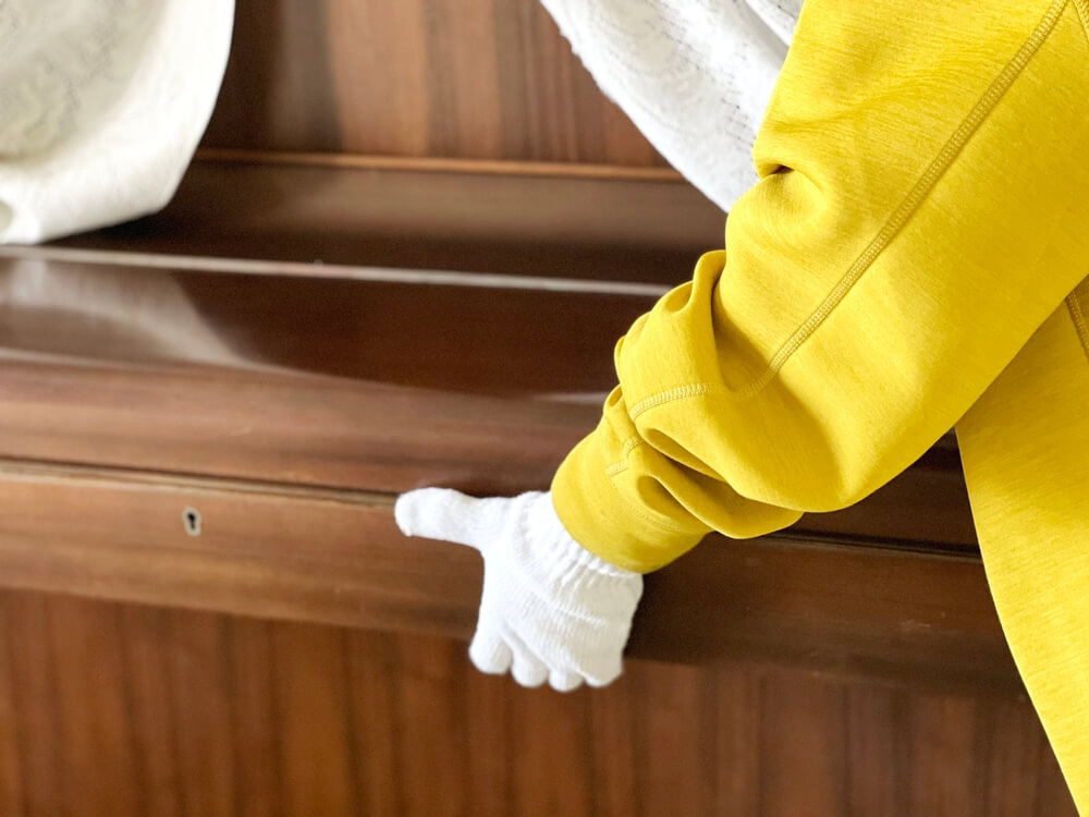 man in yellow coat and white gloves moving a piano